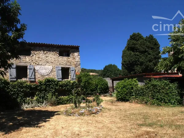 Grande maison en pierre avec un beau jardin et un garage carport