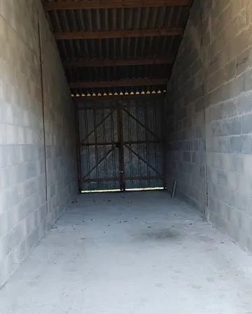 Un garage bétonné traversant de 12 m x 3 m, porte 3 m de haut