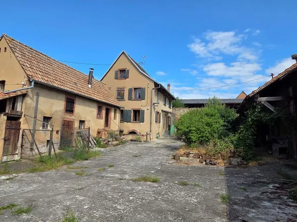 Corps de ferme comprenant une maison à rénover avec dépendances et jardin. Située au coeur du villag