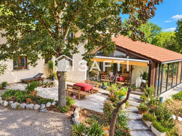 Maison avec parc arboré et véranda.