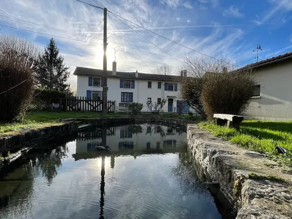 Five-bedroom longère-style house with garages, large plot of land, pond, and river view.