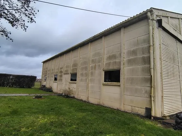 Hangar de 200 m² accessible PL, parking macadam, bâti sur 722 m² clos et constructibles.