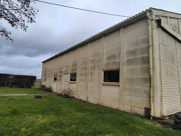 Hangar de 200 m² accessible PL, parking macadam, bâti sur 722 m² clos et constructibles.