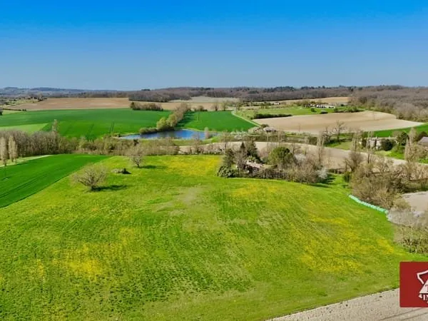 Maison en pierre avec piscine, étang et terrain.