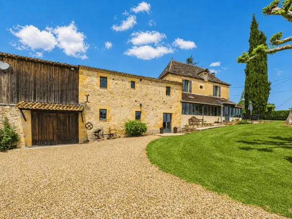 Belle maison de maître en pierre située dans un paysage vallonné en pleine campagne