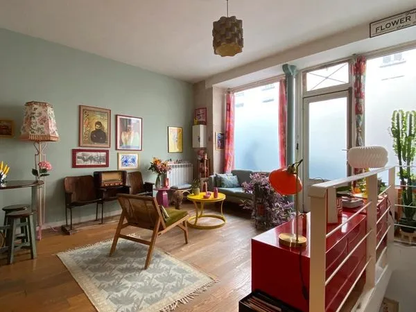 Esprit loft aux Épinettes. Pierre, lumière et hauteur sous plafond pour un RDC de 52 m² ouvert sur c
